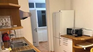 Eine kleine Küche mit Holzarbeitsplatte, einer eingebauten Mikrowelle und einem Kühlschrank.