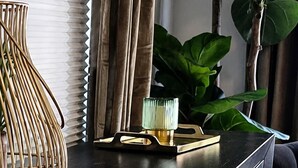 Une commode en bois foncé avec des tiroirs, un vase en osier et une petite plante posée sur le dessus.