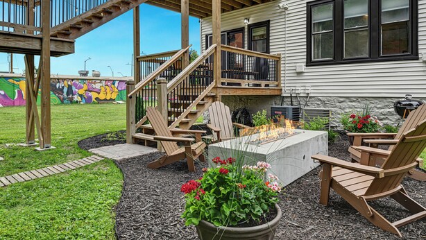 Une terrasse avec des rampes en bois, un foyer extérieur et des sièges pour profiter de l’extérieur.