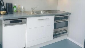 A compact kitchen with white cabinets, a stainless steel sink, and a built-in oven.