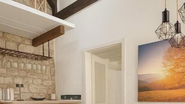 A dining area with a stone wall, wooden beams, a black table, and modern chairs.