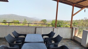 An outdoor seating area with a table and chairs, a view of the landscape, and a pergola structure.