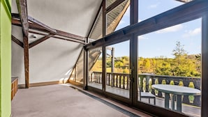 A room with a sloped ceiling, large windows, and a view of a balcony with outdoor seating. - Family-Friendly Apartment Close to Nature & Hiking Trails (Meinerzhagen)