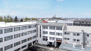 En byggnad med flera våningar, en parkeringsplats, en satellitantenn och utsikt över ett avlägset torn.