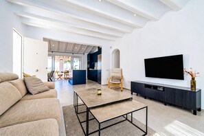 A modern living room with a sofa, coffee table, TV, and a dining area in the background. - Villa Irenal Javea, with Air Conditioning and Private Pool (Javea)