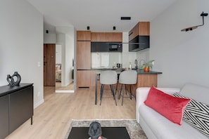 Una cocina moderna con armarios de madera, un microondas negro y un taburete de bar.