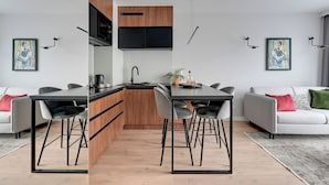 A modern kitchen with a central island, wooden cabinets, and a flat-screen TV. - Młoda Polska Apartments with parking  (Sopot)