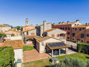 Zona residencial con edificios de piedra, una torre de campanas y un panel solar en una casa.
