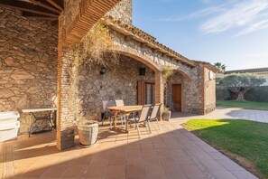 Un edificio de piedra con un patio, una mesa y sillas, y una puerta.