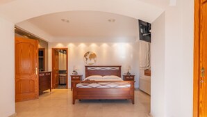 Ein Schlafzimmer mit einem hölzernen Bett, einem Nachttisch, einer Wandlampe und einer Tür zu einem Badezimmer.