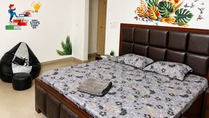 A bedroom with a bed, a bean bag chair, a wall decal, and a door. - Cozy 2 & 1 Bedroom Apartment in Sahibzada Ajit Singh Nagar (Mohali)