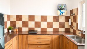 A kitchen with wooden cabinets, a built-in stove, a sink, and a tiled backsplash. - Cozy 2 & 1 Bedroom Apartment in Sahibzada Ajit Singh Nagar (Mohali)