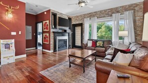 A living room with a fireplace, leather sofa, and a ceiling fan. - Sauna, Free Dollywood & More, Views! - (Gatlinburg)