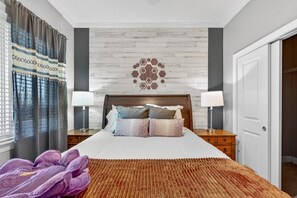 Ein Hotelzimmer mit einem Bett, zwei Nachttischen mit Lampen, einer Wand mit Muster und einer Tür.