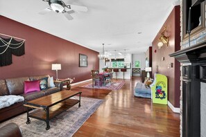A spacious living room with a sofa, coffee table, and a dog bed. There is a dining area with a table and chairs in the background. - Sauna, Free Dollywood & More, Views! - (Gatlinburg)