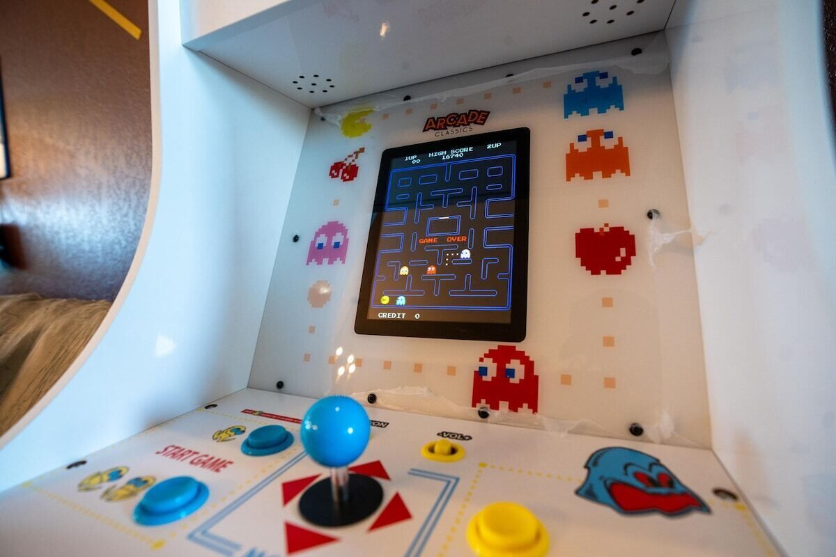 Une borne d’arcade rétro avec un jeu de labyrinthe, mettant en scène des personnages classiques des jeux d’arcade et affichant le score.