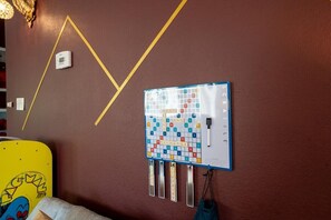 Ein Zimmer mit einem an der Wand befestigten Scrabble-Spielbrett und einem Thermostat.