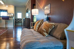 A room with a wooden floor, a sofa with cushions, a lamp, and a wall-mounted picture. - Sauna, Free Dollywood & More, Views! - (Gatlinburg)