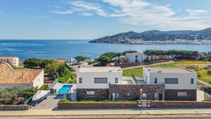A residential area with modern houses, a swimming pool, and a view of the sea. - Villa Cala Prona : Private Mediterranean Retreat (Girona)