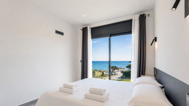A hotel room with a large bed, a view of the sea, and a modern design. - Villa Cala Prona : Private Mediterranean Retreat (Girona)