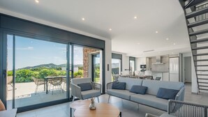 A modern living area with a sofa, chairs, a dining table, and a view of the outdoors. - Villa Cala Prona : Private Mediterranean Retreat (Girona)