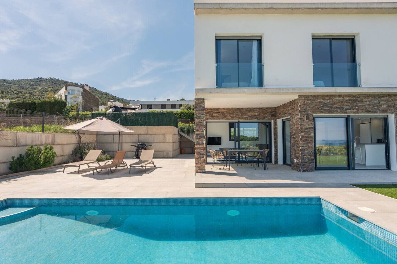 Una casa moderna con piscina, mobiliario de exterior y vistas del paisaje circundante.