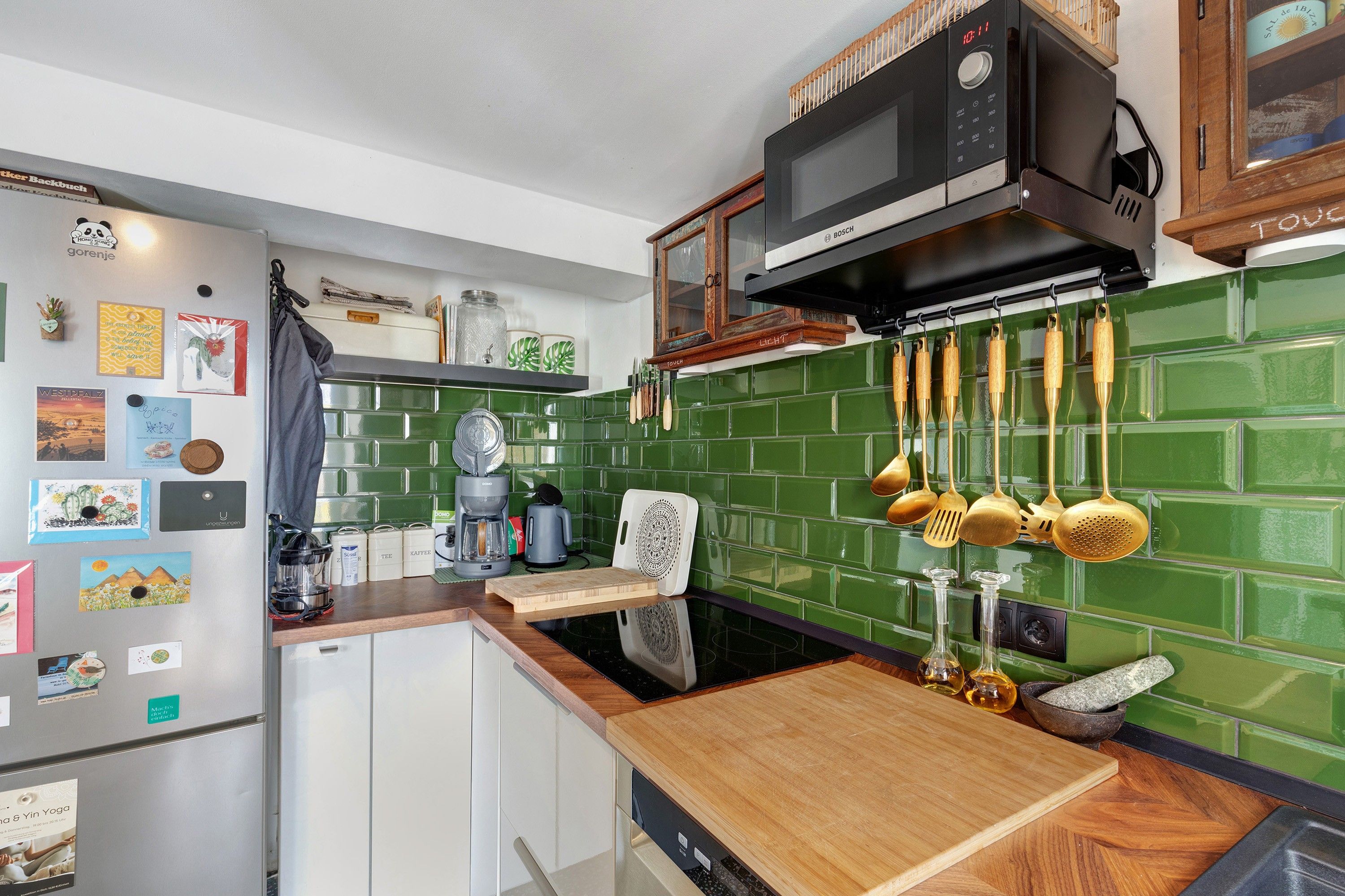 Una cocina con microondas, cafetera y varios utensilios de cocina colgados en la pared.