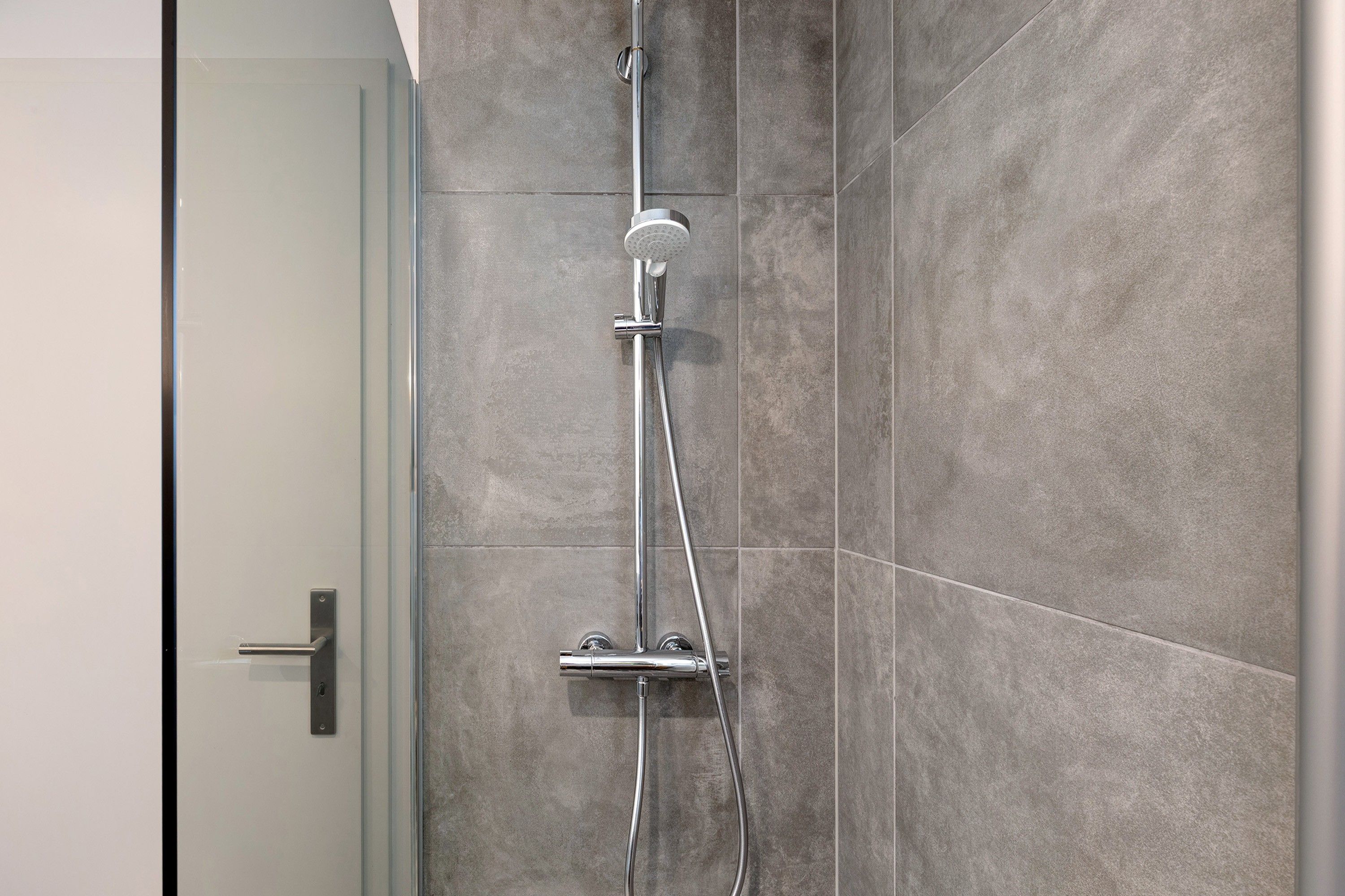 Eine moderne Dusche mit Handbrause und fest installierter Wandarmatur.