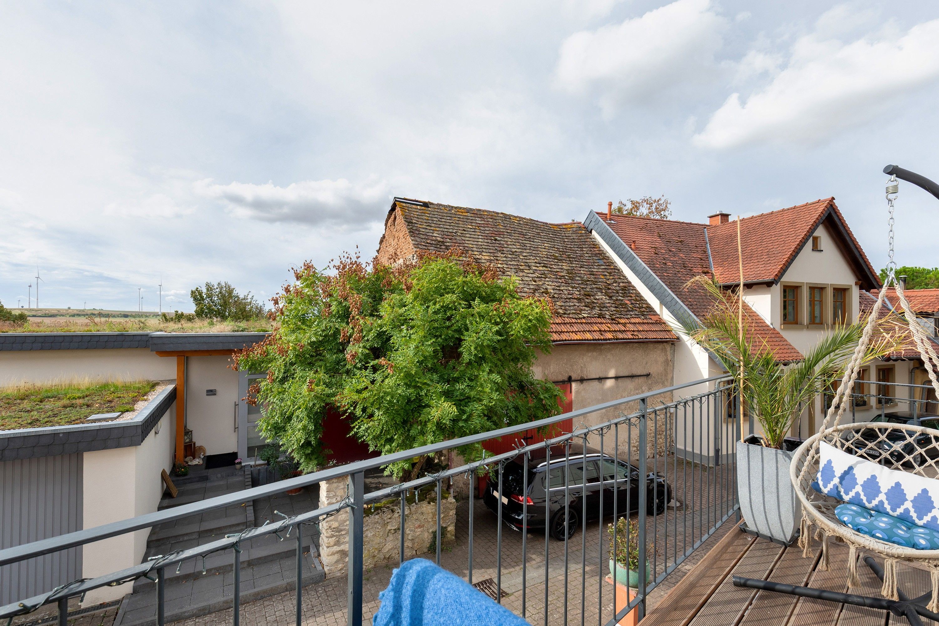 A residential area with a house, a car parked in the driveway, and a hammock chair.
