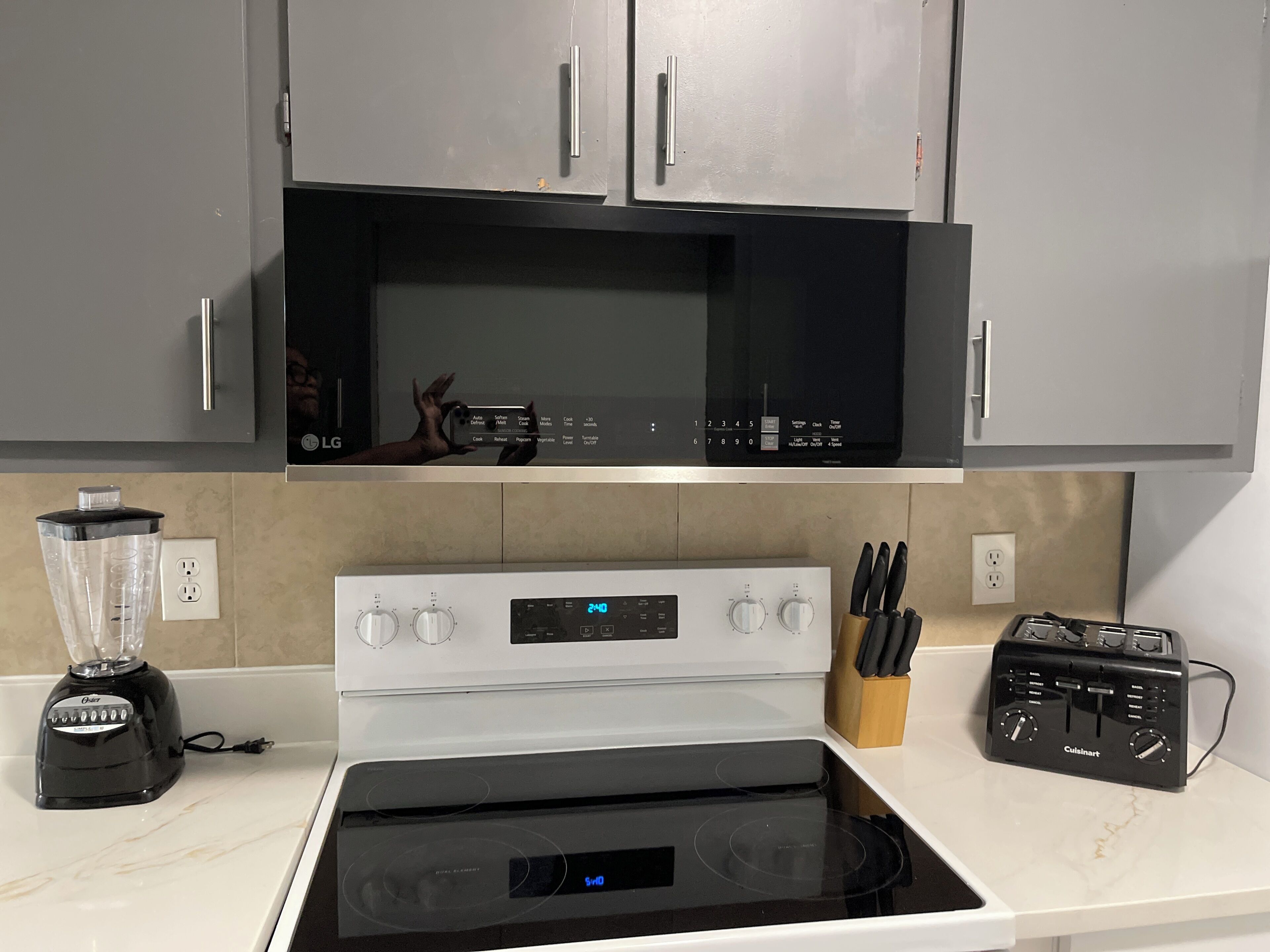 A kitchen with a microwave, stove, and blender.