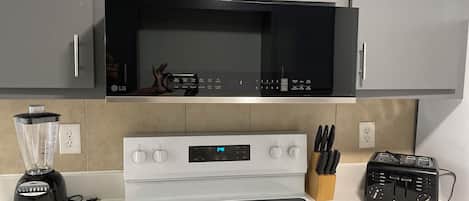 A kitchen with a microwave, stove, and blender.