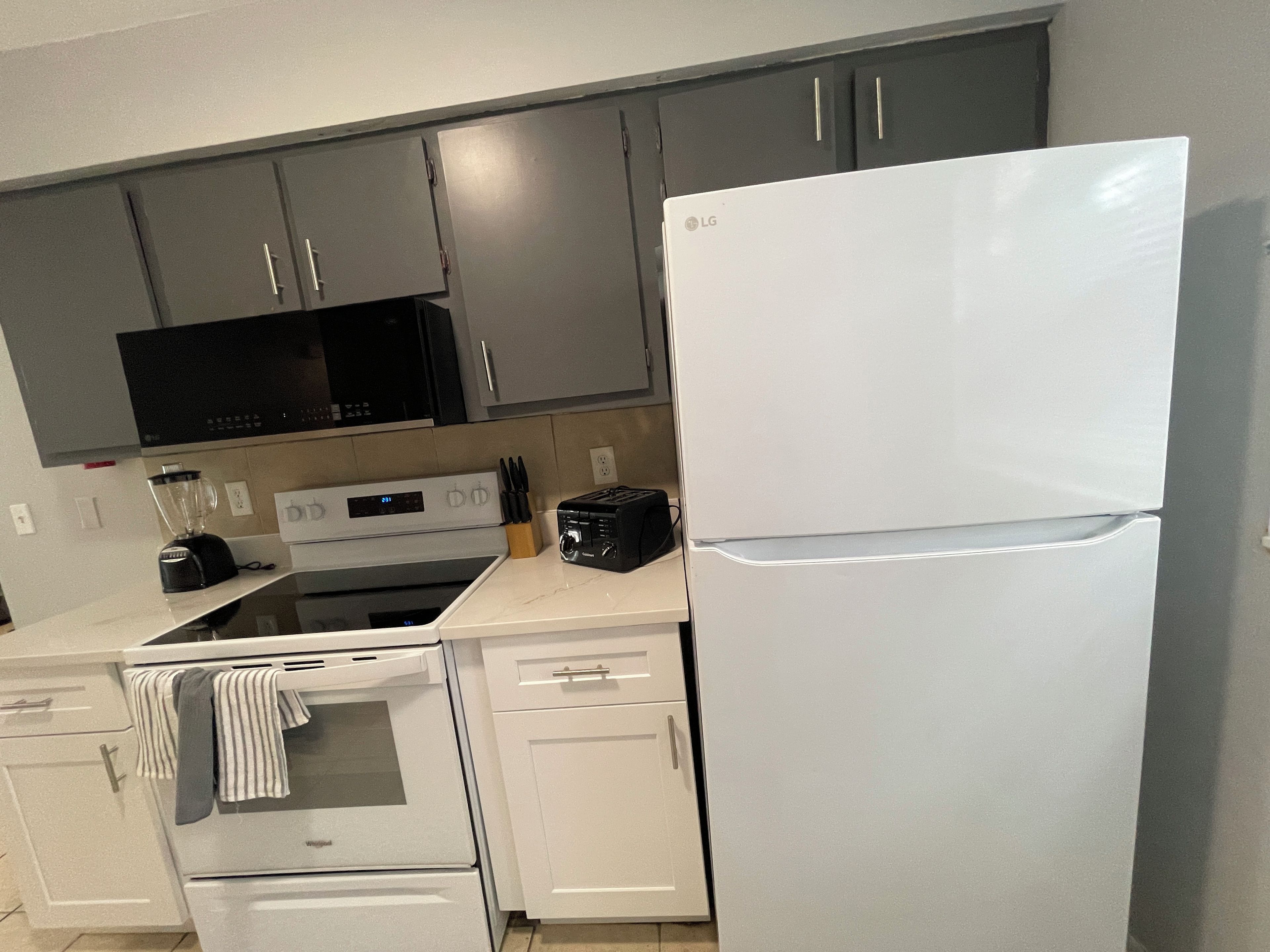 A kitchen with a white refrigerator, a microwave, a stove, and a toaster.
