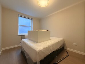 Ein Schlafzimmer mit einem Bett, einem Fenster und einer Heizung.