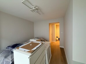 Ein Zimmer mit einem Bett, einem Schreibtisch und einem Stuhl. Ein Flur führt zu einem weiteren Zimmer.