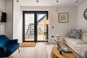 A modern living room with a blue chair, a sofa, a lamp, a bookshelf, and a view of a staircase outside. - 1 Min Walk to Euston Station Modern Apartment (London)