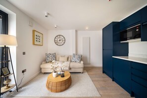 Ein modernes Wohnzimmer mit einer Couch, einem Couchtisch und einer Küchenzeile mit blauen Schränken.