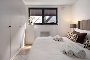 A bedroom with a bed, pillows, a window, and a radiator. - 1 Min Walk to Euston Station Modern Apartment (London)
