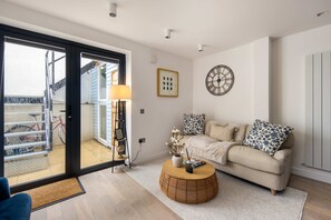 Ein Wohnzimmer mit einer Couch, einem runden Couchtisch, einer Lampe und einer Wanduhr.