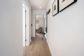 Ein Korridor mit Holzboden, weißen Wänden und einem gerahmten Bild an der Wand.