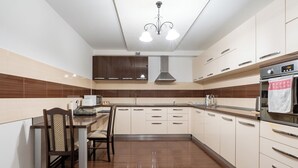 Una cocina moderna con comedor, que incluye una isla central, armarios de madera oscura y un horno de acero inoxidable.