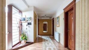 Un pasillo con piso de madera, un radiador, una puerta numerada y un aire acondicionado de pared.