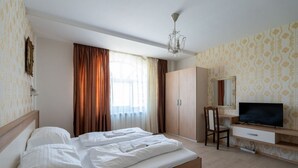 Una habitación de hotel con cama, escritorio con silla, televisor y armario.