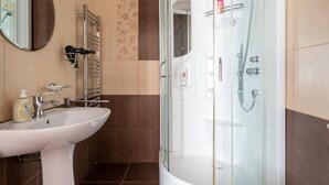A bathroom with a white sink, a glass shower enclosure, and a towel rack. - FarawayHomes Aparthotel Vienna Airport #1 (Bruck an der Leitha)