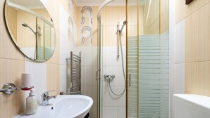 Un baño con lavamanos, espejo, ducha e inodoro.