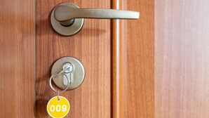 Una puerta de madera con un ojo de cerradura y un llavero con una etiqueta amarilla.