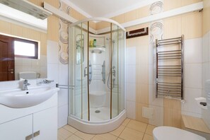 Un baño moderno con ducha de vidrio, un lavabo blanco y un perchero para toallas.