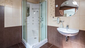 Een badkamer met een douche in een glazen cabine, een wastafel en een spiegel.