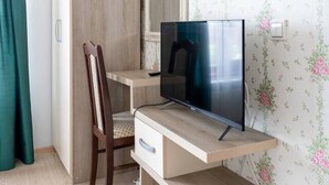 Een slaapkamer met een bed, een bureau met een computer, een stoel en een kledingkast.