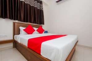 Una cama bien hecha con cabecera de madera, ropa de cama blanca y detalles en rojo.