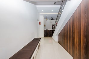 Un pasillo con un banco, una escalera y un extintor en la pared.